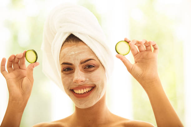 istock Woman with face mask holding cucumbers slice 1180961026
