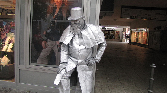 Frankfurt, Germany - May 26, 2010: Photo showing one of many street performers taken in Frankfurt, Germany. He is standing in the city street, dressed in a silver costume and is acting as a silver statue, a tourist attraction.