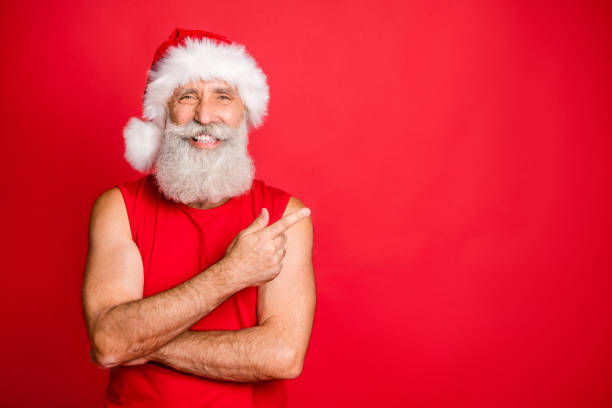 스포티 한 크리스마스 아버지의 초상화 그의 검지 웃는 추천, 빨간 배경 위에 고립 된 산타 클로스 모자 모자를 착용 하는 겨울 판매 - men gray hair vitality healthy lifestyle 뉴스 사진 이미지