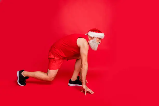 Ready steady go. Full length profile side photo of focused santa claus, ready to run race wearing sports wear cap isolated over red background