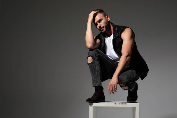 istock Thoughtful man adjusting his hair while squatting on a chair 1180968342