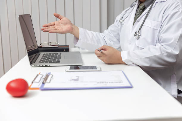 istock Midsection Of Doctor Pointing At Laptop In Office 1180969103