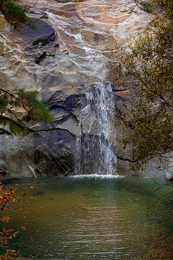 Tall Bridalveil waterfall flows over Lake shore cliff