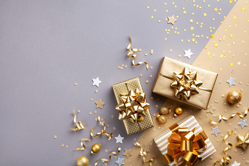 Golden gift or present boxes with golden bows and confetti top view and flat lay. Christmas background.