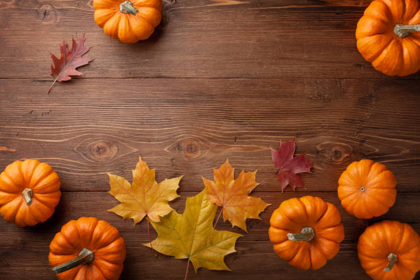 istock Autumn Thanksgiving background. Pumpkins and leaves on rustic table top view. 1180973245
