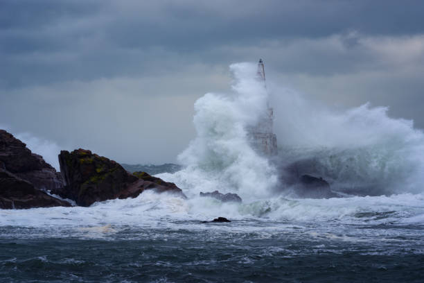 big wave against old lighthouse in the port of ahtopol, black sea, bulgaria on a moody stormy day. danger, dramatic scene. - storm lighthouse cloudscape sea imagens e fotografias de stock