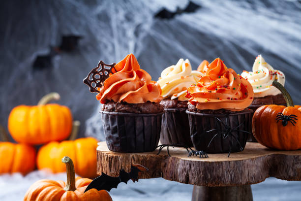 istock Halloween cupcakes and pumpkins on dark web background. Sweets for holiday party. 1180973683
