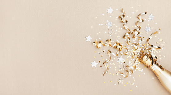 Celebration background with golden champagne bottle, confetti stars and party streamers. Christmas, birthday or wedding concept. Flat lay style.
