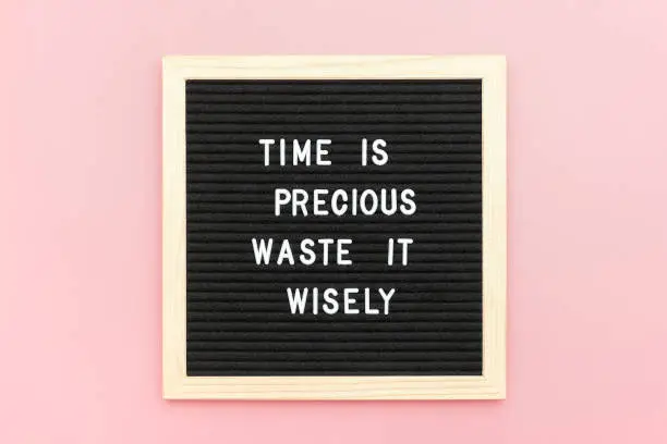 Time is precious waste it wisely. Motivational quote on letterboard on pink background. Top view Flat lay Copy space Concept inspirational quote of the day.