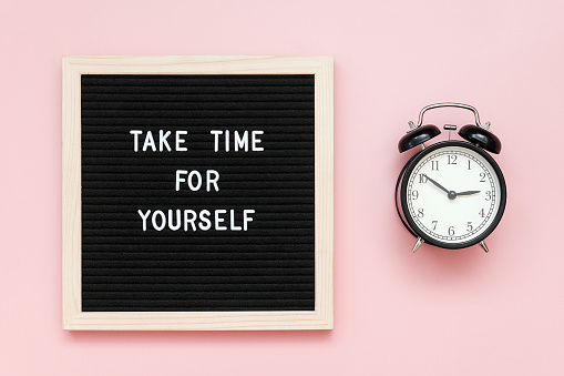 Take time for yourself. Motivational quote on letterboard and black alarm clock on pink background. Top view Flat lay Copy space Concept inspirational quote of the day.