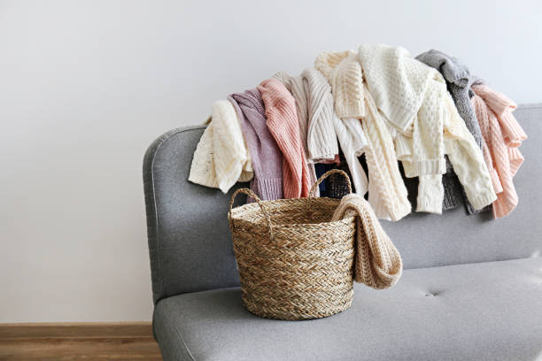 istock Bunch of sweaters of different material and knitting pattern in pile on gray sofa. 1180977626