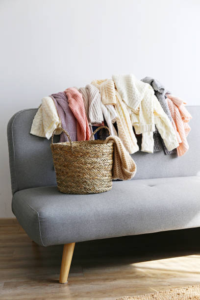 istock Bunch of sweaters of different material and knitting pattern in pile on gray sofa. 1180977633