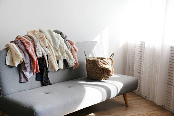 istock Bunch of sweaters of different material and knitting pattern in pile on gray sofa. 1180977639
