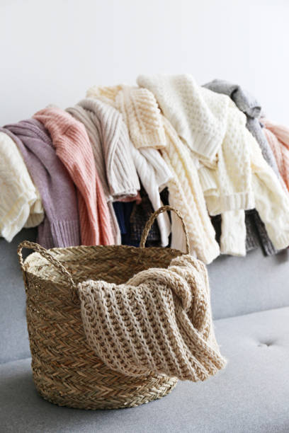 istock Bunch of sweaters of different material and knitting pattern in pile on gray sofa. 1180977644