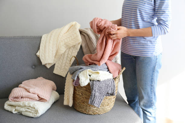 istock Bunch of sweaters of different material and knitting pattern in pile on gray sofa. 1180977667