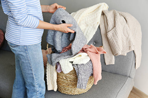 istock Bunch of sweaters of different material and knitting pattern in pile on gray sofa. 1180977693
