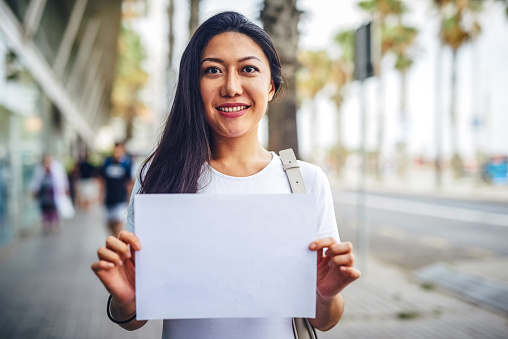 Cropped portrait of an attractive young woman standing on the street and holding up a poster while sight-seeing in Spain