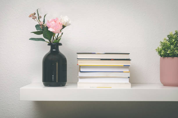 istock shelf on white wall with books and flower pots 1180979736