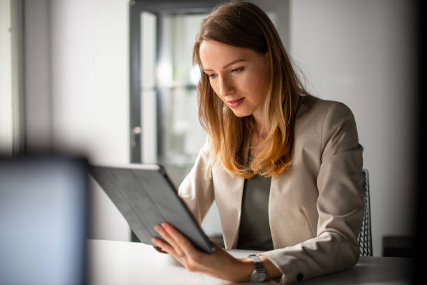istock Young woman typing on digital tablet in her office 1180980825
