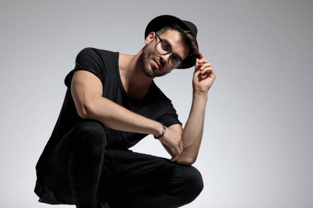istock casual man standing crouched and fixing his hat 1180983463