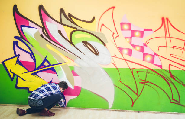 istock Man painting graffiti on orange wall 1180989208