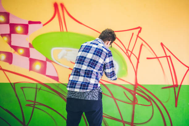 istock Man painting graffiti on orange wall 1180989228