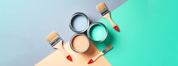 istock Metal paint cans and paint brushes on multicolor background. Top view. Copy space. Trendy green color concept 1180989935