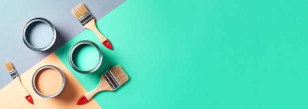 Metal paint cans and paint brushes on multicolor background. Top view. Copy space. Trendy green color concept