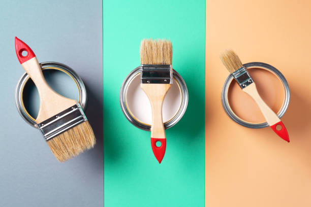 istock Metal paint cans and paint brushes on multicolor background. Top view. Copy space. Trendy green color concept 1180990032