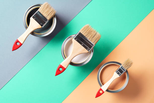 istock Metal paint cans and paint brushes on multicolor background. Top view. Copy space. Trendy green color concept 1180990057