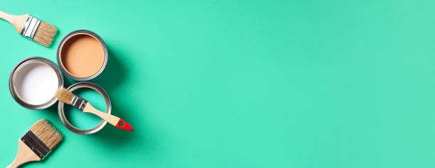 istock Paint brushes and open paint cans with on trendy green background. Top view, copy space. Appartment renovation, repair, building and home design concept. 1180990233