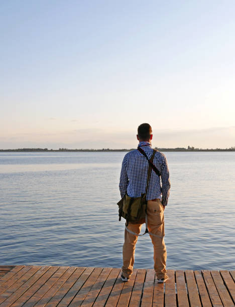 istock Man seen from the back standing at a lake 1180996651