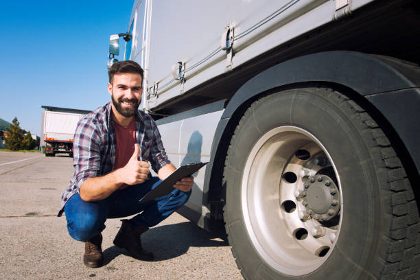 親指を持つトラック運転手は、タイヤの状態を検査し、圧力をチェックします。乗車前のトラックの準備。輸送サービス。 - truck semi truck blue truck driver ストックフォトと画像