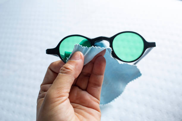istock Woman's left hand cleaning black sunglasses by microfibre cleaning cloths, On white background, Close up & Macro shot, Selective focus, Optical concept 1181000044