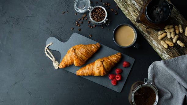 istock Croissants with raspberries lying on a dark background. View from above. 1181004123