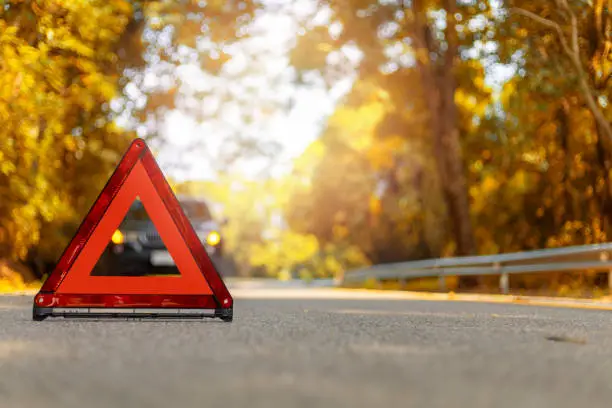 Photo of Red triangle, red emergency stop sign, red emergency symbol and black car stop and park on road.