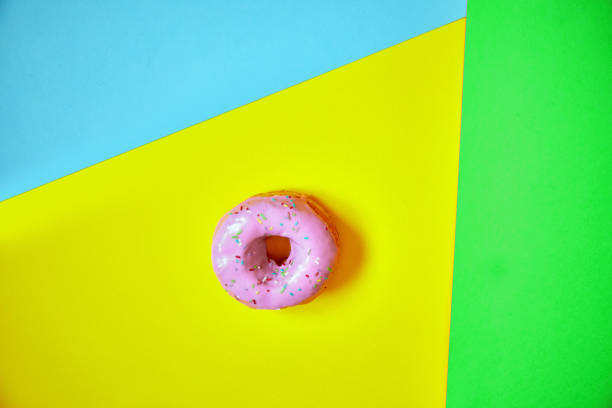 istock Sprinkled pink donut on colorful background. 1181004311