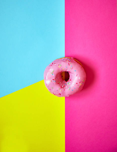 istock Sprinkled pink donut on colorful background. 1181004338