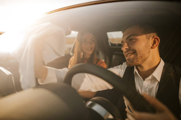istock Couple having fun in car while man polishing windshield with cloth 1181004349