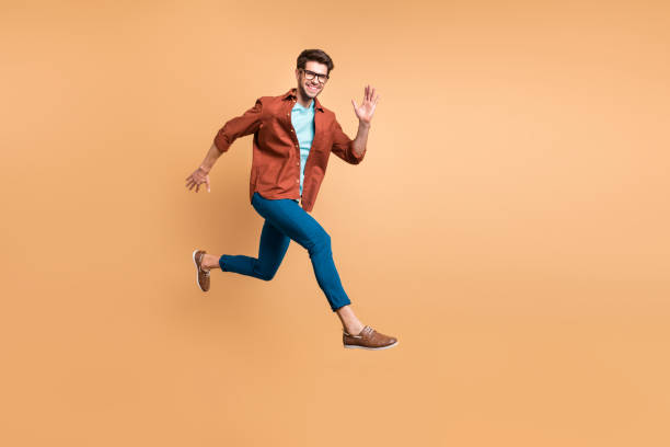 istock Full length body size view of his he nice attractive cheerful cheery glad active successful guy leader jumping in air running fast hurry-up meeting isolated over beige color pastel background 1181007908