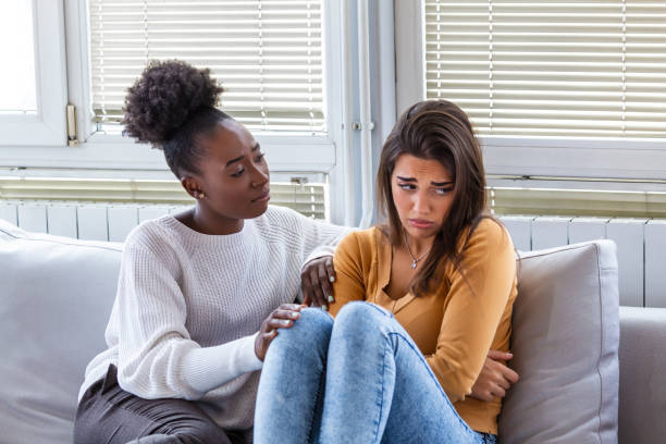 fille triste et amis de soutien essayant de résoudre un problème. deux femmes diverses tristes parlant à la maison. amis féminins se soutenant mutuellement. problèmes, concept d'amitié et de soins - child grief mourner disappointment photos et images de collection