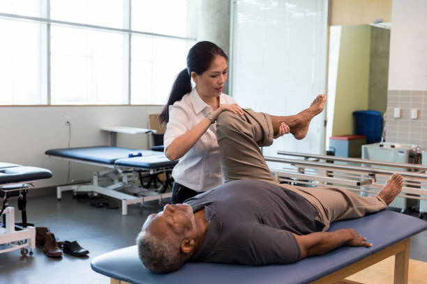 istock Physical therapist focuses on properly bending mature man's leg 1181007985