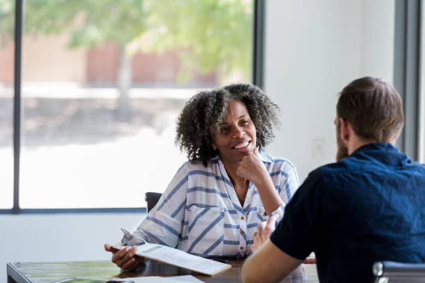 Mature businesswoman talks withe male colleague Confident mature businesswoman attentively listens during a meeting with a male associate. career counseling stock pictures, royalty-free photos & images