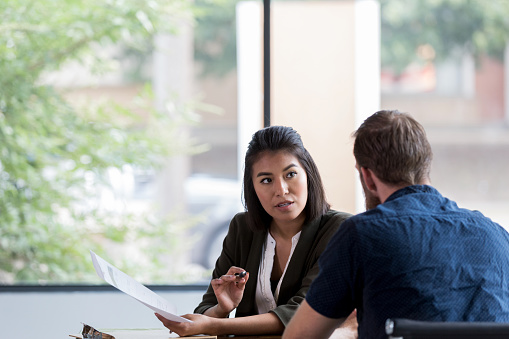 Hispanic businesswoman gestures during a serious conversation with a male colleague.