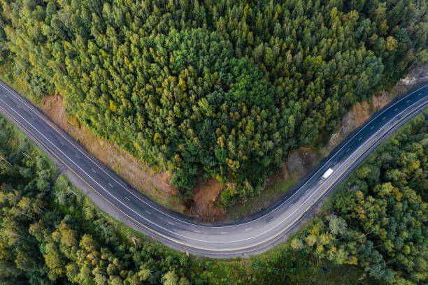 Top down aerial view of mountain road curve among green forest trees. Small cargo truck on the highway P-258 road on the shore of Baikal Lake near Baikalsk, Buryatia, Russia siberia summer stock pictures, royalty-free photos & images