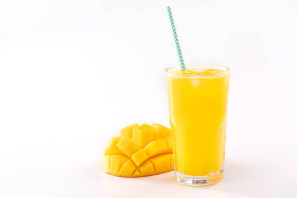 Fresh tropical mango juice with beautiful diced pulp and striped paper straw isolated on white background table, close up, cut out, clipping path.
