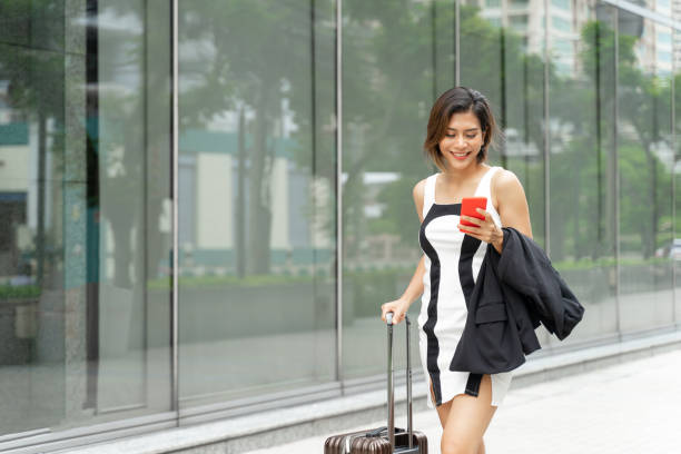 istock Young working woman use smartphone and walking with suitcase 1181010926