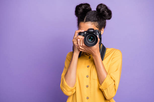 海外観光の写真を手に持つ驚くべき暗い肌の女性の写真は、黄色のシャツのズボンを着用紫色の背景を着用 - 写真を撮る 写真 ストックフォトと画像