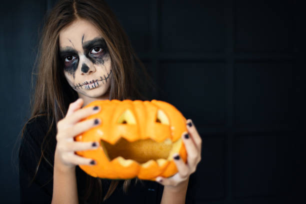 istock A girl with scary makeup and a halloween pumpkin 1181018243