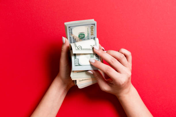 istock Top view of a businesswoman's hands counting one hundred and different dollar banknotes on colorful background. Success and wealth concept 1181018496